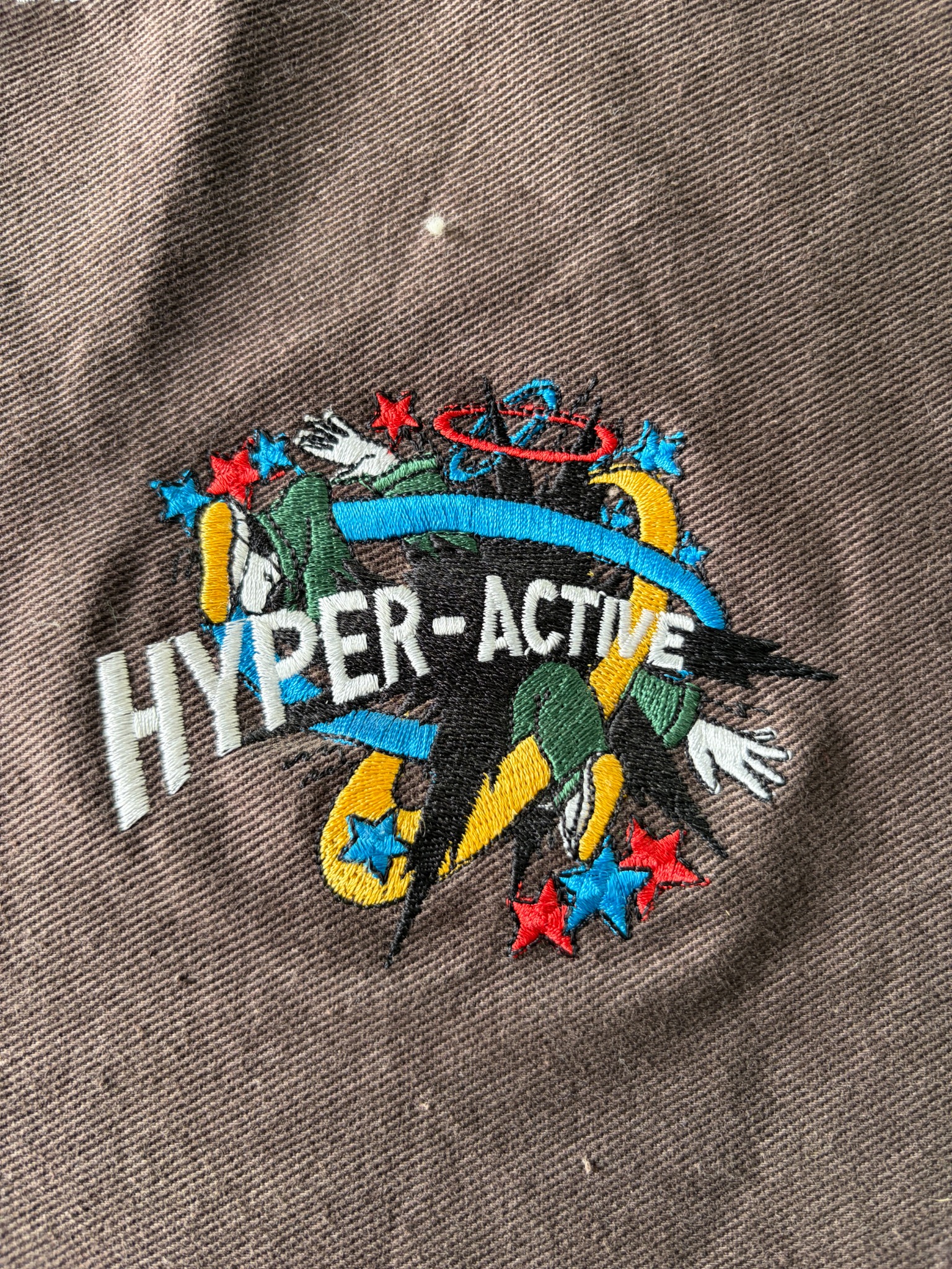 Colourful Hyper-Active character embroidery on brown fabric